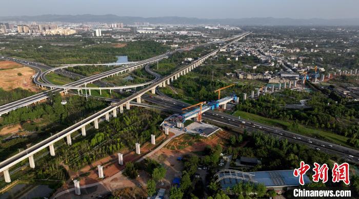 航拍正在建設(shè)的跨越成都繞城高速公路連續(xù)梁施工現(xiàn)場，旁邊依次為已運(yùn)營的成渝高速鐵路和機(jī)場高速公路?！⒅铱?攝