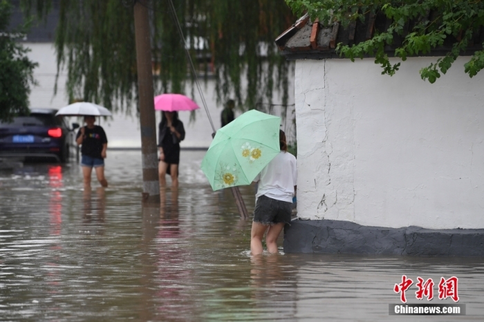 7月31日，市民行走在雨中的北京房山區(qū)瓦窯頭村。北京市氣象臺(tái)當(dāng)日10時(shí)發(fā)布分區(qū)域暴雨紅色預(yù)警信號(hào)。北京市水文總站發(fā)布洪水紅色預(yù)警，預(yù)計(jì)當(dāng)日12時(shí)至14時(shí)，房山區(qū)大石河流域?qū)⒊霈F(xiàn)紅色預(yù)警標(biāo)準(zhǔn)洪水。<a target='_blank' href='/'><p  align=