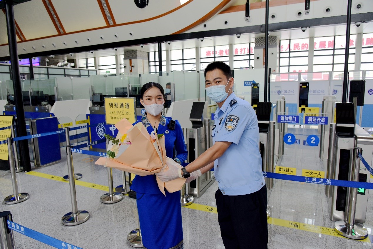 磨憨出入境邊防檢查站民警為中老鐵路第100萬(wàn)名出入境旅客，D888次國(guó)際旅客列車?yán)蠐爰藙?wù)員森達(dá)拉·妮緹婭（Sengdala Nitiya），送上鮮花。黃遠(yuǎn)飛 攝