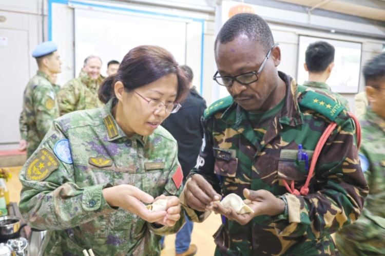 圖為維和官兵與外軍人員共同包餃子。胡光明攝