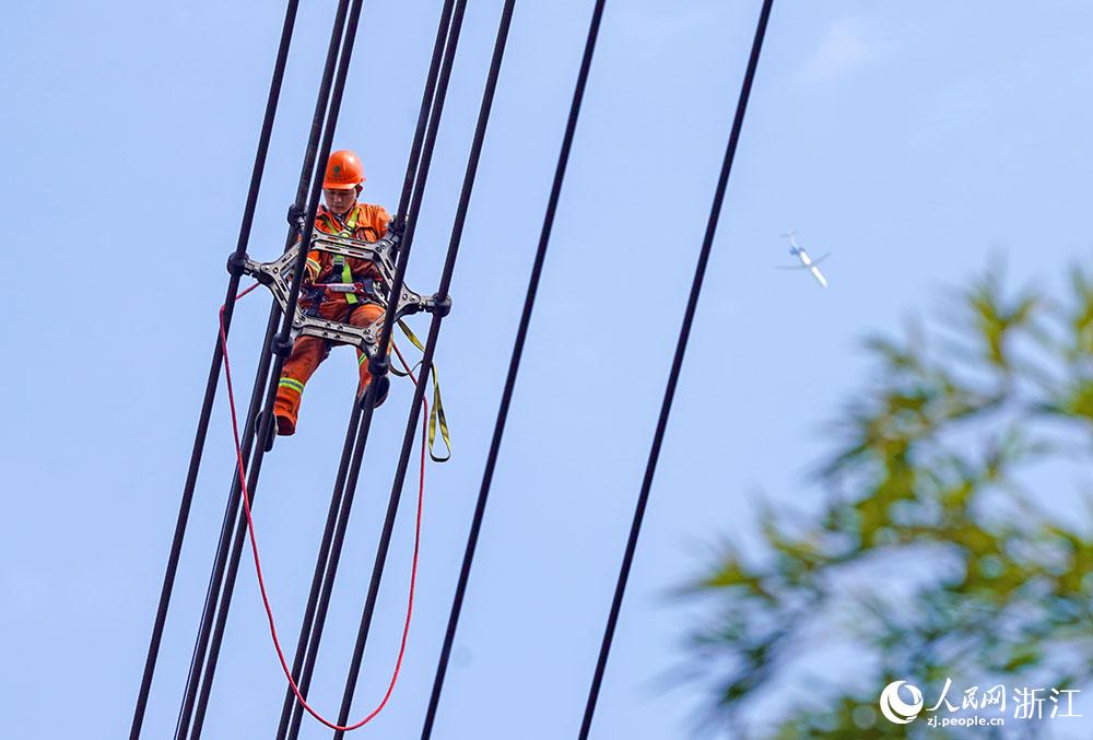 3月11日，在浙江省諸暨市河上鎮(zhèn)，浙江省送變電工程有限公司檢修人員在高空的導(dǎo)線上進(jìn)行線路檢修維護(hù)。人民網(wǎng) 章勇濤攝