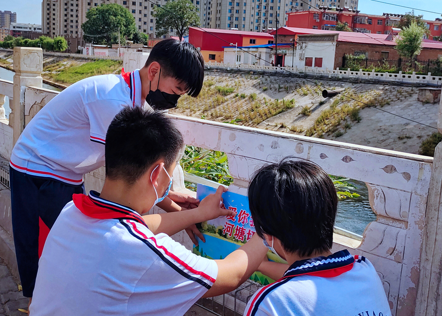 徐水小學(xué)學(xué)雷鋒志愿者在瀑河河邊張貼防溺水警示標語。 徐水區(qū)委宣傳部供圖