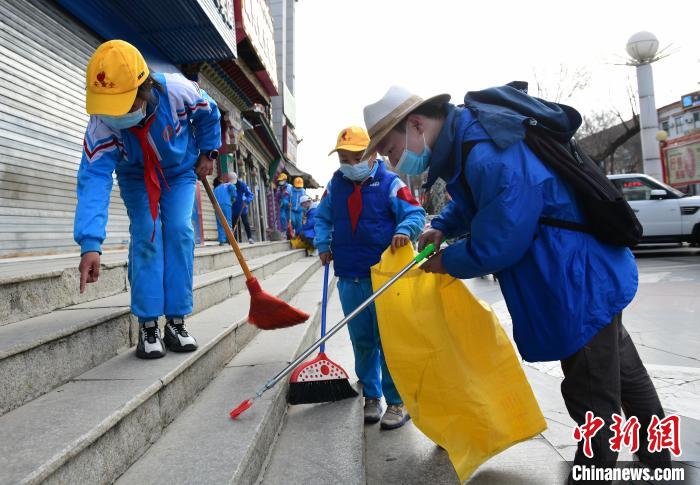 圖為拉薩市小學(xué)生打掃街道?！∝暩聛?lái)松 攝