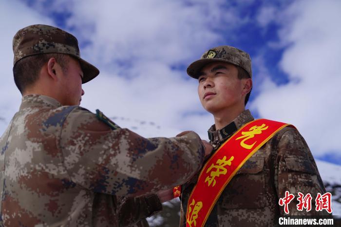 排長王朝偉(圖左)給退伍老兵佩戴大紅花?！∥鞑厣侥宪姺謪^(qū)某團(tuán)供圖