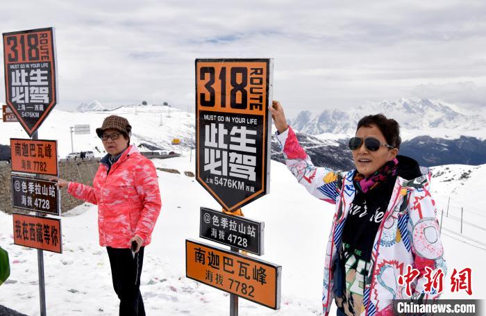 圖為5月14日，西藏林芝色季拉山觀景臺，游客與南迦巴瓦峰合影。　李林 攝