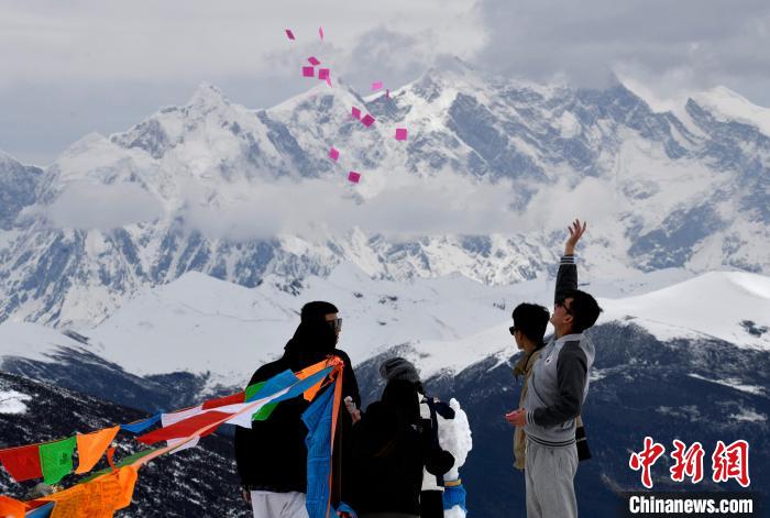 圖為5月14日，游客在西藏林芝色季拉山觀景臺拋灑“隆達”(風馬旗，藏族民眾的一種祈福方式)?！±盍?攝