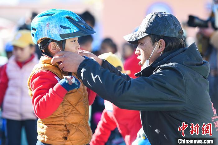 圖為拉薩市實(shí)驗(yàn)幼兒園孩子在教練的幫助下穿戴頭盔?！『闻罾?攝