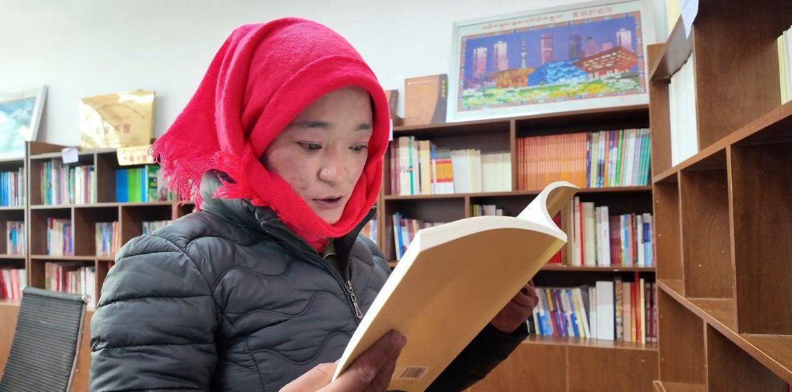一名婦女正在認真閱讀書籍。申扎縣融媒體中心供圖