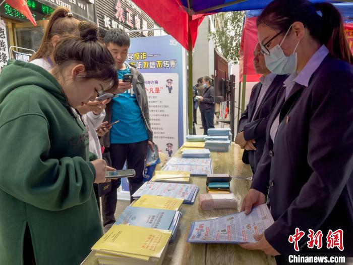 圖為工作人員正在向路過市民介紹國(guó)家反詐中心軟件的功能。　謝牧 攝