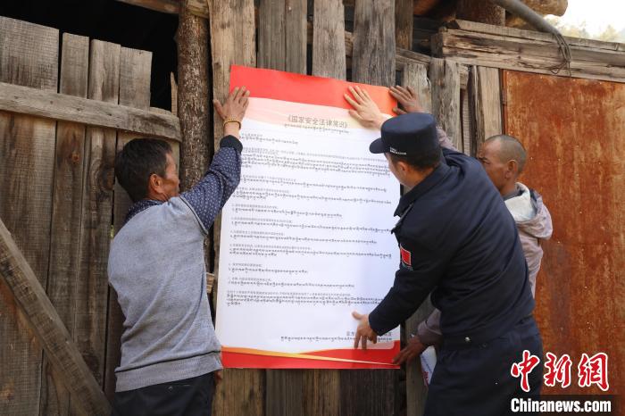 圖為亞?wèn)|邊檢站民警與駐地邊民群眾共同張貼國(guó)家安全知識(shí)教育海報(bào)。　亞?wèn)|邊檢站 供圖